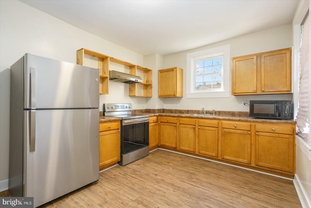 kitchen featuring open shelves, a sink, light wood-style floors, appliances with stainless steel finishes, and wall chimney exhaust hood