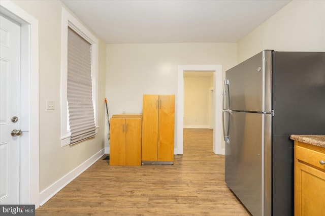 kitchen with baseboards, light wood finished floors, and freestanding refrigerator