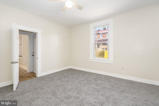 carpeted spare room with baseboards and a ceiling fan