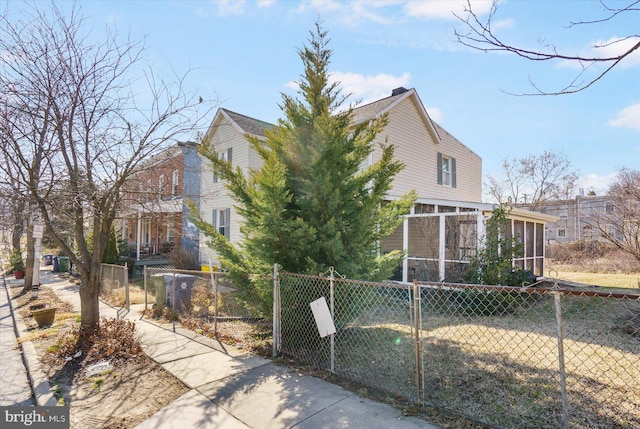 view of side of property with a fenced front yard and a sunroom