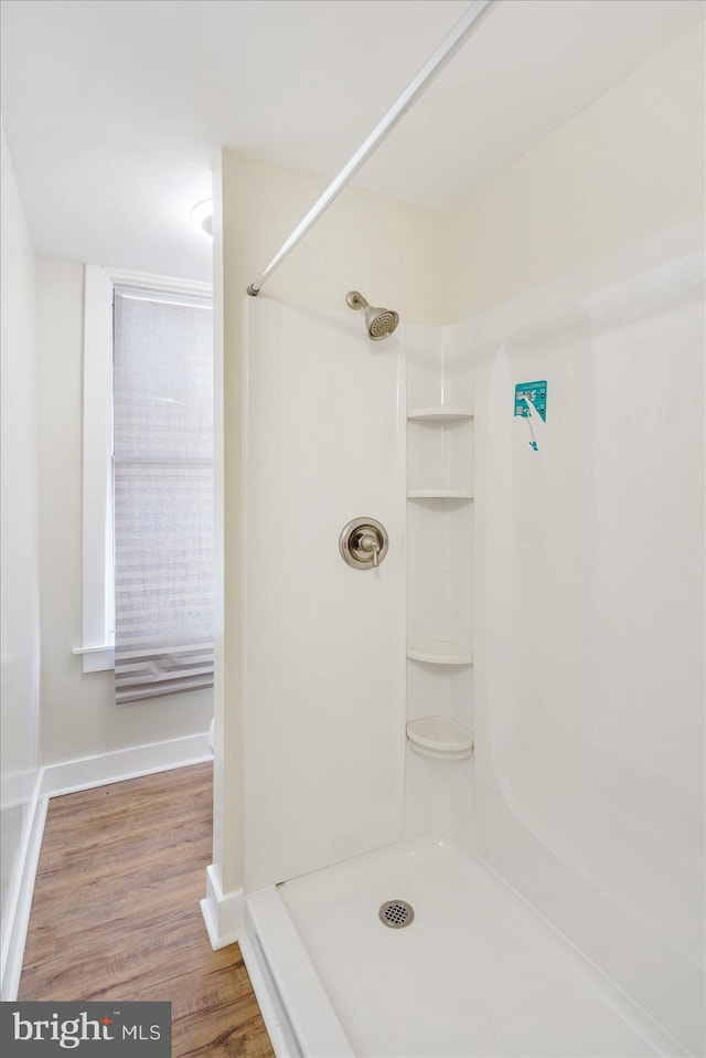 bathroom featuring baseboards, walk in shower, and wood finished floors