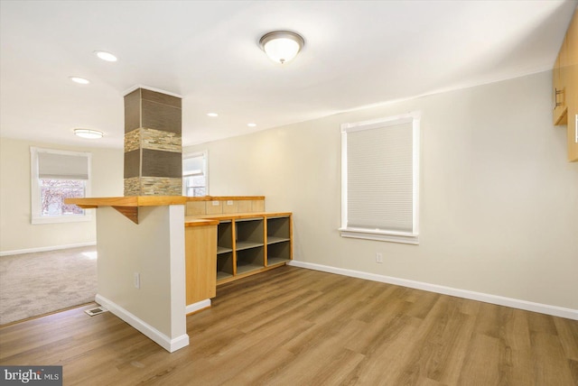 kitchen with a breakfast bar area, wood finished floors, visible vents, baseboards, and recessed lighting