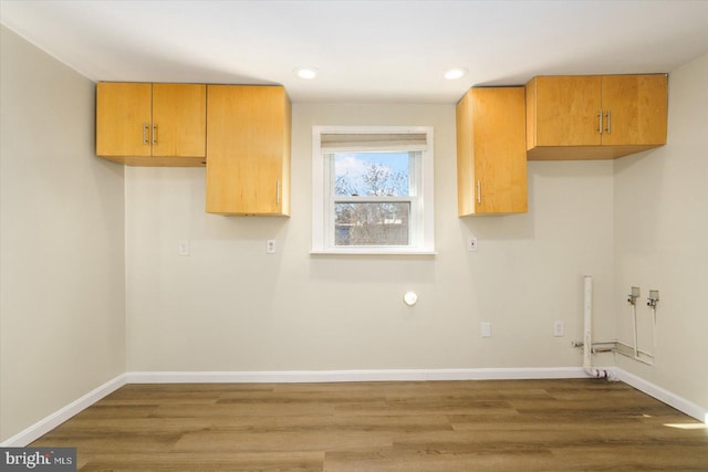 clothes washing area featuring wood finished floors, baseboards, cabinet space, recessed lighting, and washer hookup