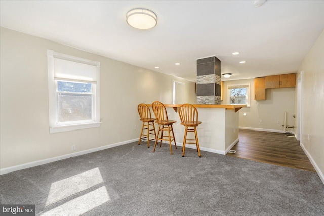 kitchen featuring a breakfast bar, a peninsula, recessed lighting, and baseboards