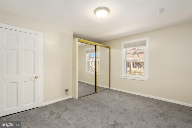 unfurnished bedroom featuring a closet, visible vents, baseboards, and carpet floors