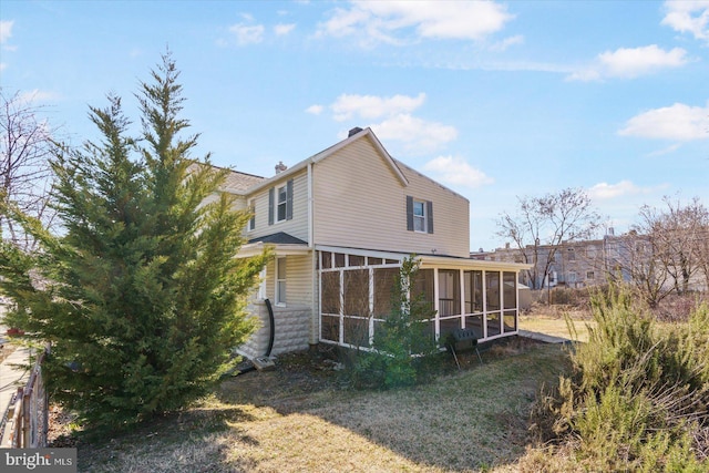 rear view of property featuring a chimney and a sunroom