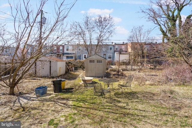 view of yard featuring a residential view, a storage unit, and an outdoor structure