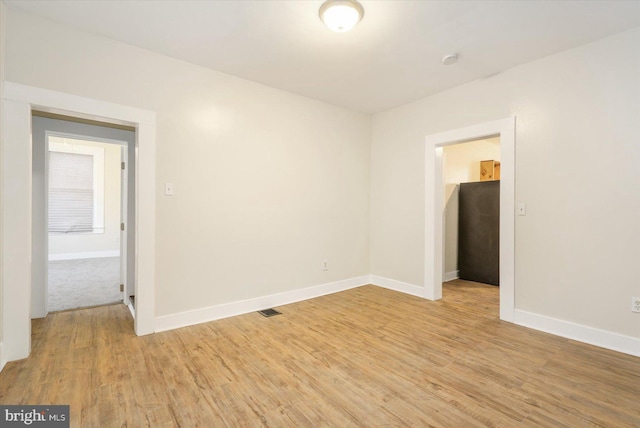 spare room with visible vents, baseboards, and light wood finished floors