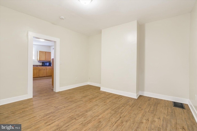 spare room featuring light wood-style flooring, baseboards, and visible vents