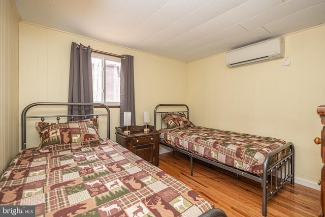 bedroom with a wall mounted AC and wood finished floors