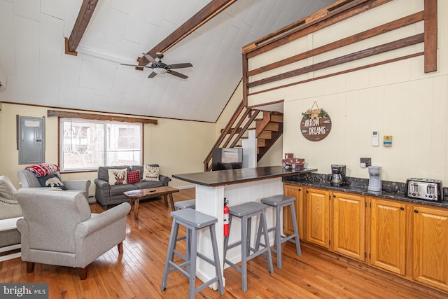 interior space featuring stairway, a ceiling fan, lofted ceiling with beams, electric panel, and light wood-style floors