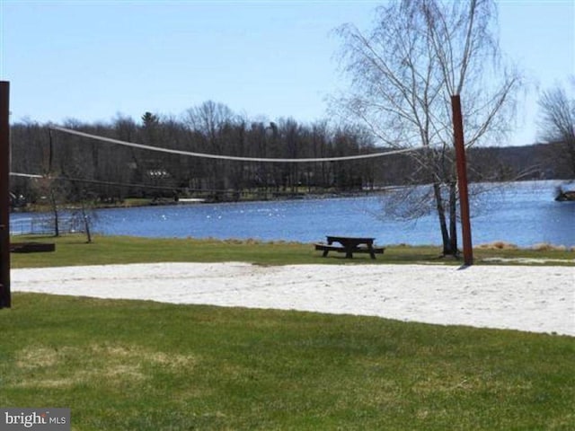 surrounding community featuring volleyball court, a lawn, and a water view