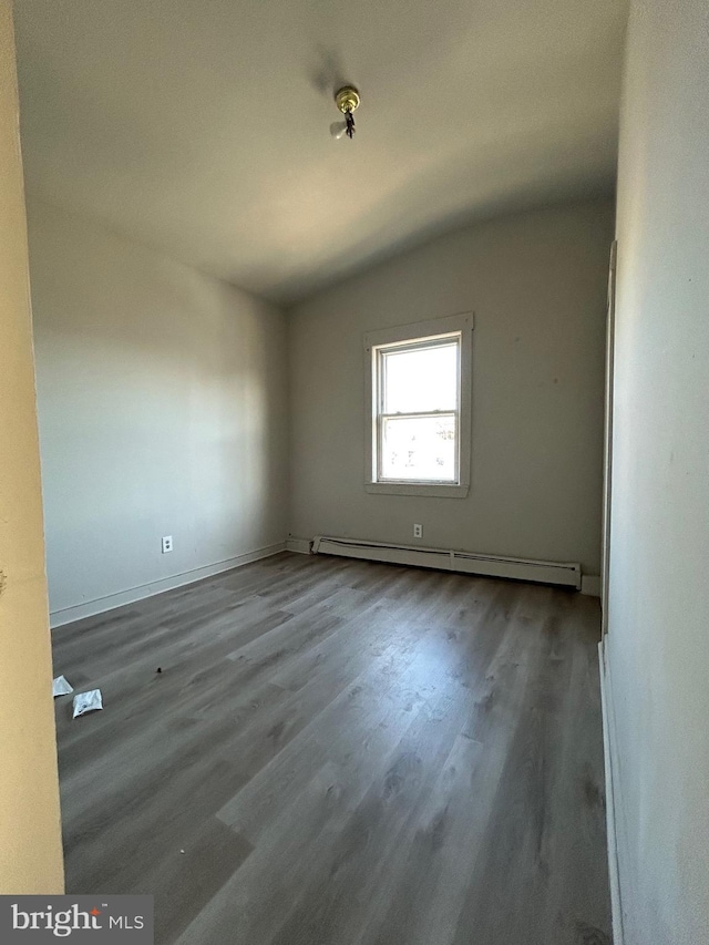 empty room featuring wood finished floors, lofted ceiling, and a baseboard radiator