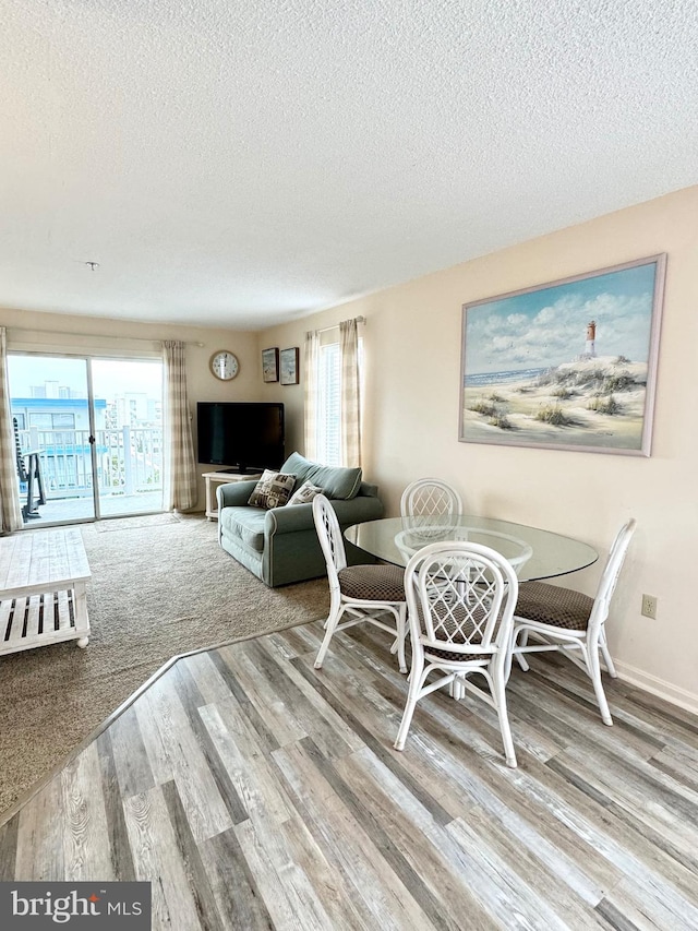 dining room with baseboards, a textured ceiling, and wood finished floors