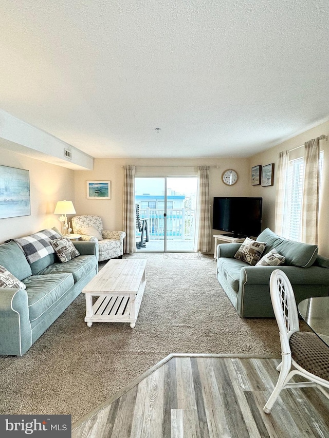 living room with visible vents, a textured ceiling, and wood finished floors