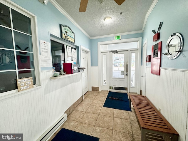 foyer entrance featuring ceiling fan, a textured ceiling, ornamental molding, and wainscoting