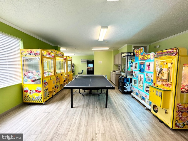 recreation room featuring light wood finished floors, a textured ceiling, and crown molding