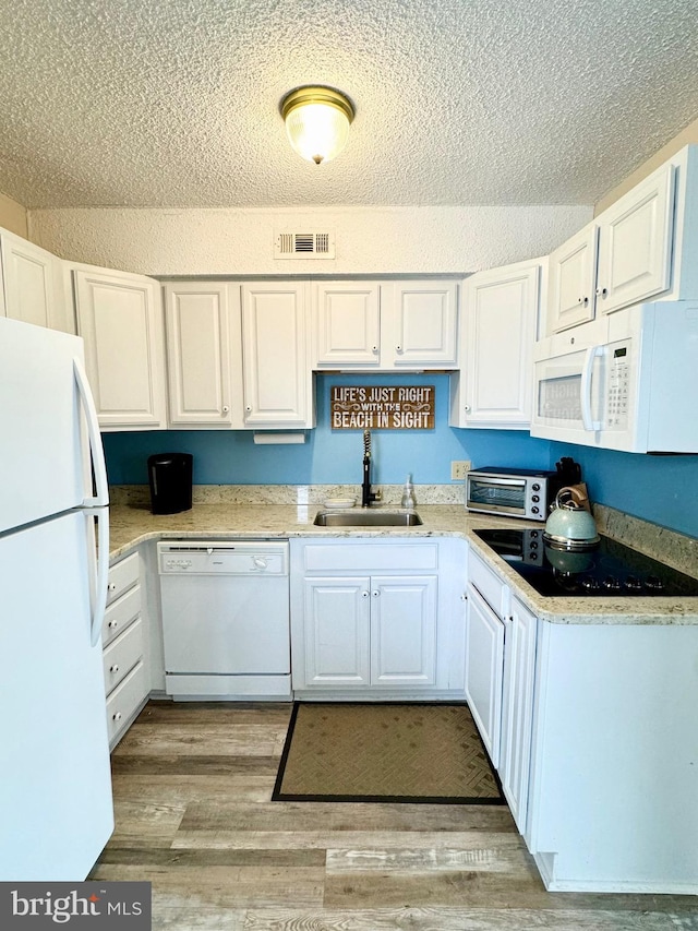 kitchen featuring visible vents, light wood-style flooring, white appliances, white cabinetry, and a sink