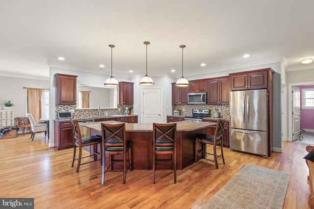 kitchen with a breakfast bar, a sink, appliances with stainless steel finishes, and a kitchen island