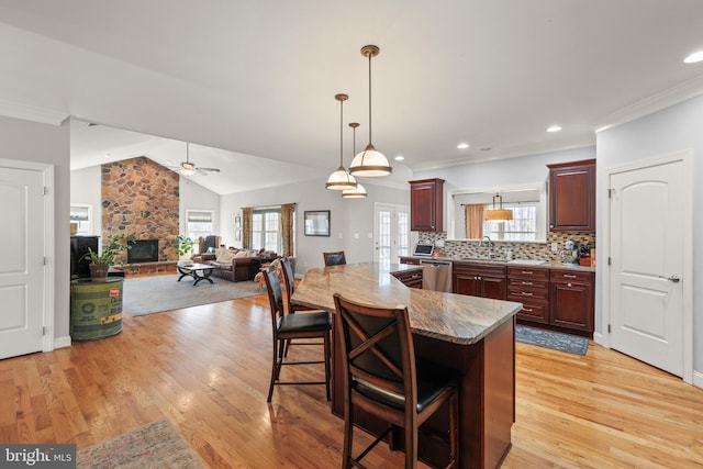 kitchen featuring tasteful backsplash, dishwasher, a kitchen bar, a fireplace, and a sink