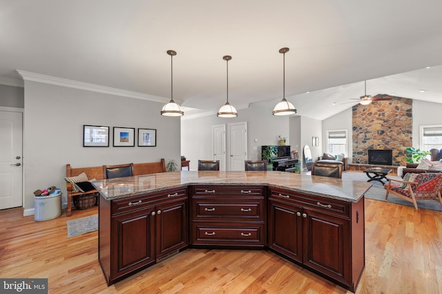 kitchen with light wood finished floors, ornamental molding, ceiling fan, vaulted ceiling, and decorative light fixtures