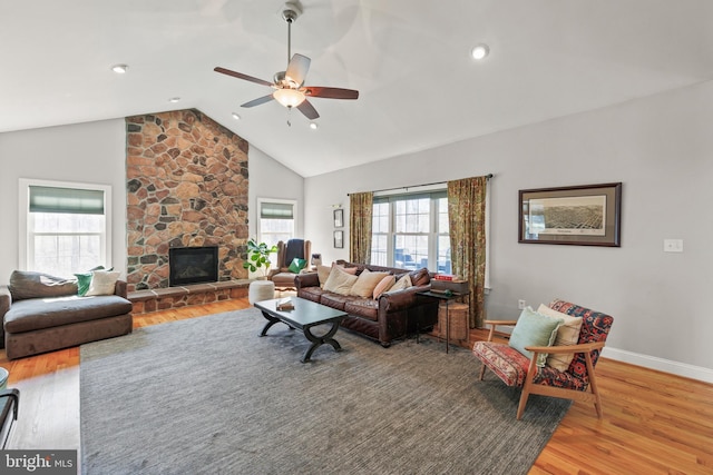 living area with a fireplace, wood finished floors, baseboards, and ceiling fan