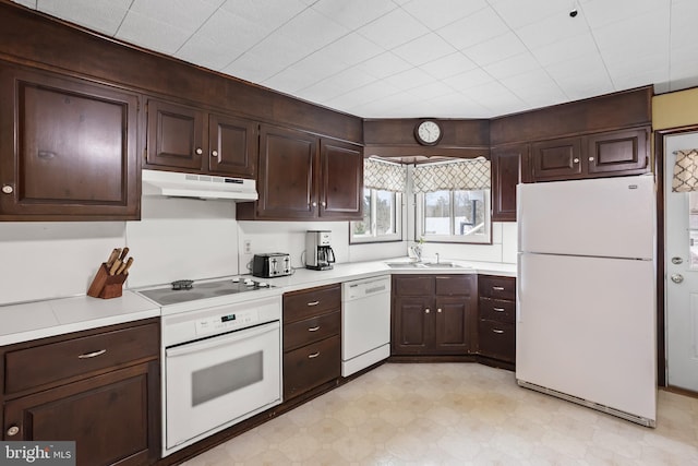 kitchen with under cabinet range hood, a sink, white appliances, light countertops, and light floors