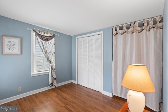 unfurnished bedroom with dark wood finished floors, baseboards, and a closet