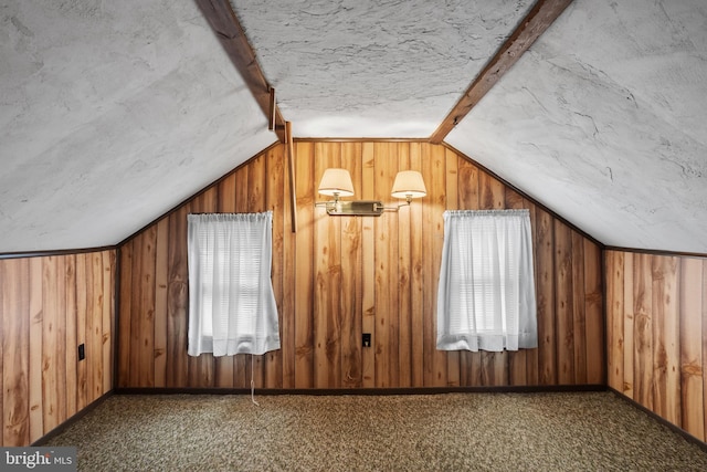 additional living space with vaulted ceiling, baseboards, wood walls, and carpet floors