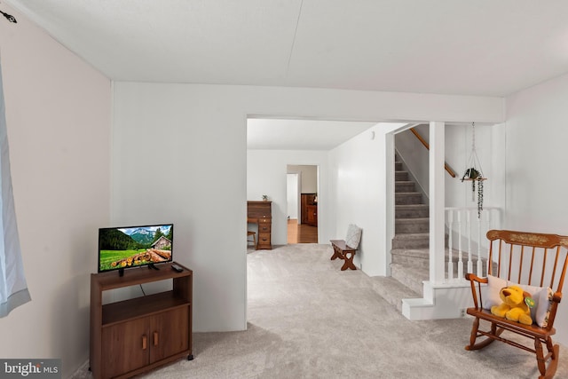 sitting room featuring light carpet and stairs