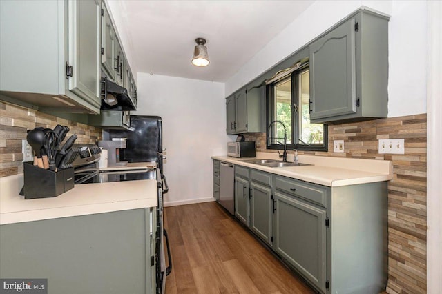 kitchen with backsplash, gray cabinets, appliances with stainless steel finishes, and a sink