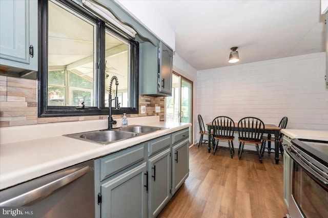 kitchen with a sink, light countertops, gray cabinetry, light wood-style floors, and stainless steel appliances