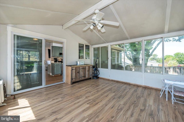 unfurnished sunroom featuring vaulted ceiling with beams, ceiling fan, and wood finished floors