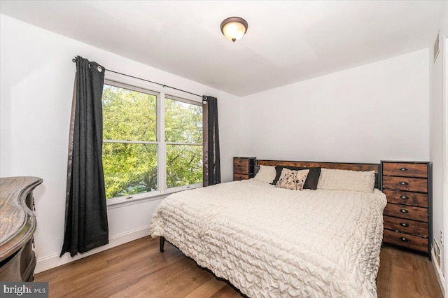 bedroom featuring baseboards, multiple windows, and wood finished floors