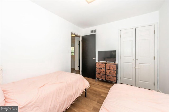 bedroom featuring a closet, wood finished floors, and visible vents