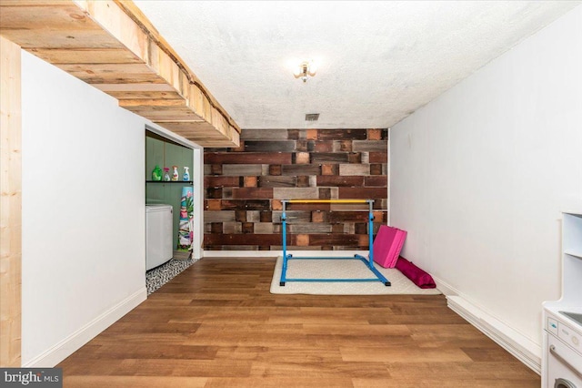 rec room featuring a textured ceiling, visible vents, washer / clothes dryer, wood finished floors, and baseboards
