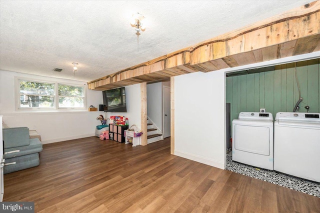 interior space with laundry area, a textured ceiling, baseboards, wood finished floors, and washer and clothes dryer