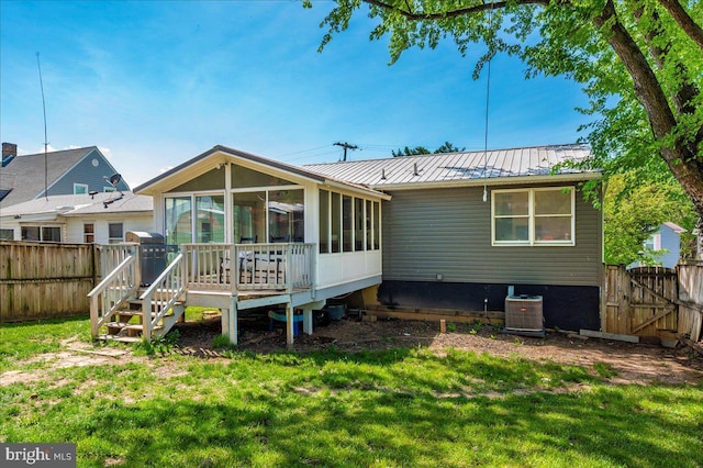 back of property with a sunroom, a fenced backyard, a lawn, and central air condition unit