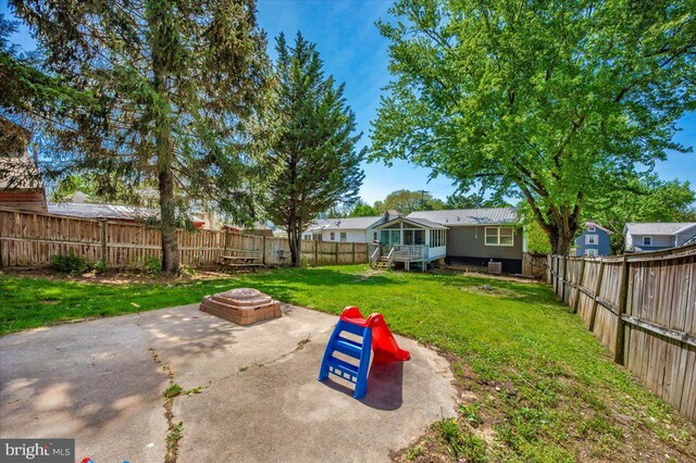 view of yard with a sunroom, a fire pit, a fenced backyard, and a patio area
