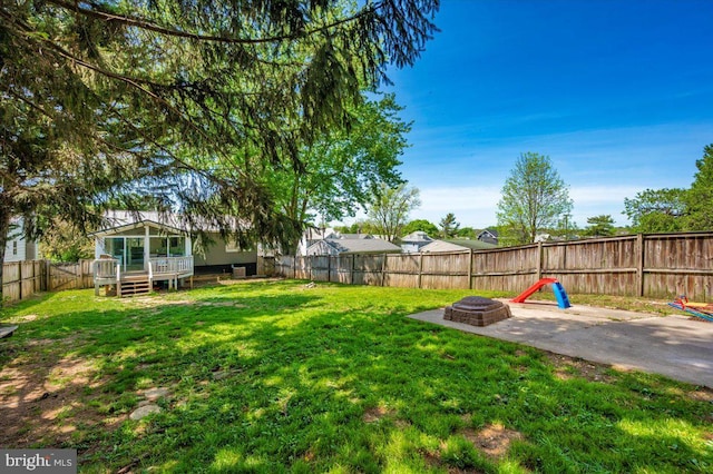view of yard featuring a patio, a deck, a fenced backyard, and an outdoor fire pit