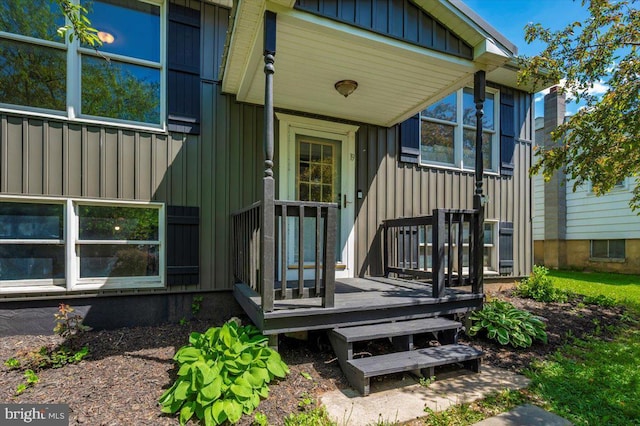 view of exterior entry with a wooden deck and board and batten siding