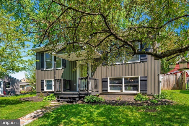 view of front of property featuring board and batten siding, fence, and a front yard