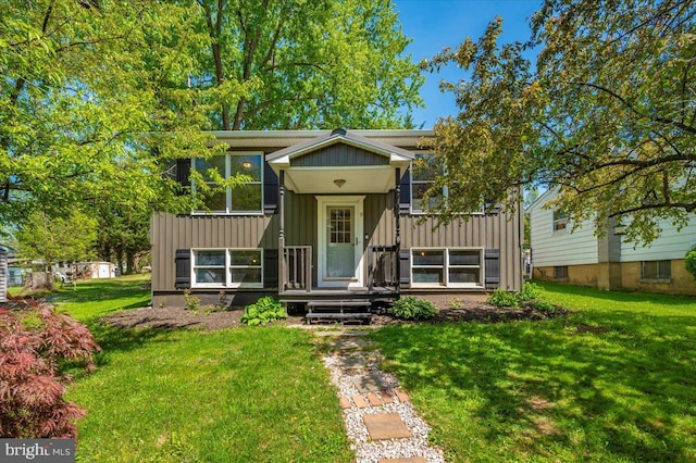 raised ranch featuring a front lawn and board and batten siding