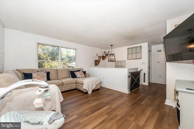 living area with dark wood-type flooring, baseboards, and a notable chandelier