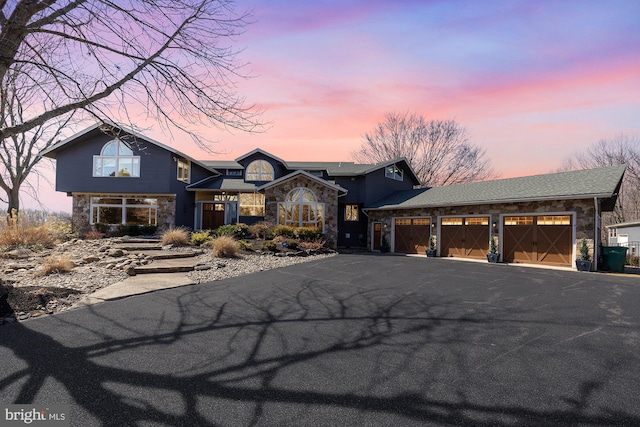 view of front of house featuring aphalt driveway, an attached garage, and stone siding