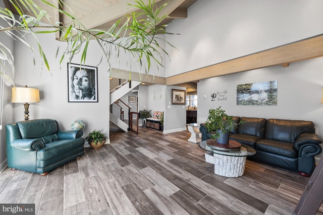 living area with wood finish floors, beamed ceiling, high vaulted ceiling, baseboards, and stairs