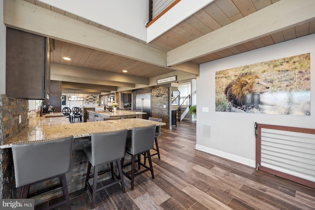 kitchen featuring baseboards, dark brown cabinetry, beamed ceiling, a peninsula, and dark wood-style floors