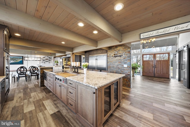 kitchen featuring a notable chandelier, beamed ceiling, built in refrigerator, and wood finished floors