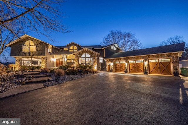 view of front of property with aphalt driveway, an attached garage, and stone siding