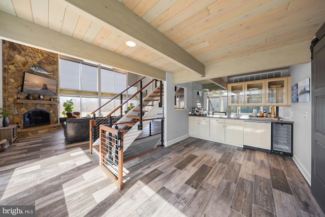 interior space featuring dark wood-type flooring, wine cooler, glass insert cabinets, dishwasher, and beamed ceiling